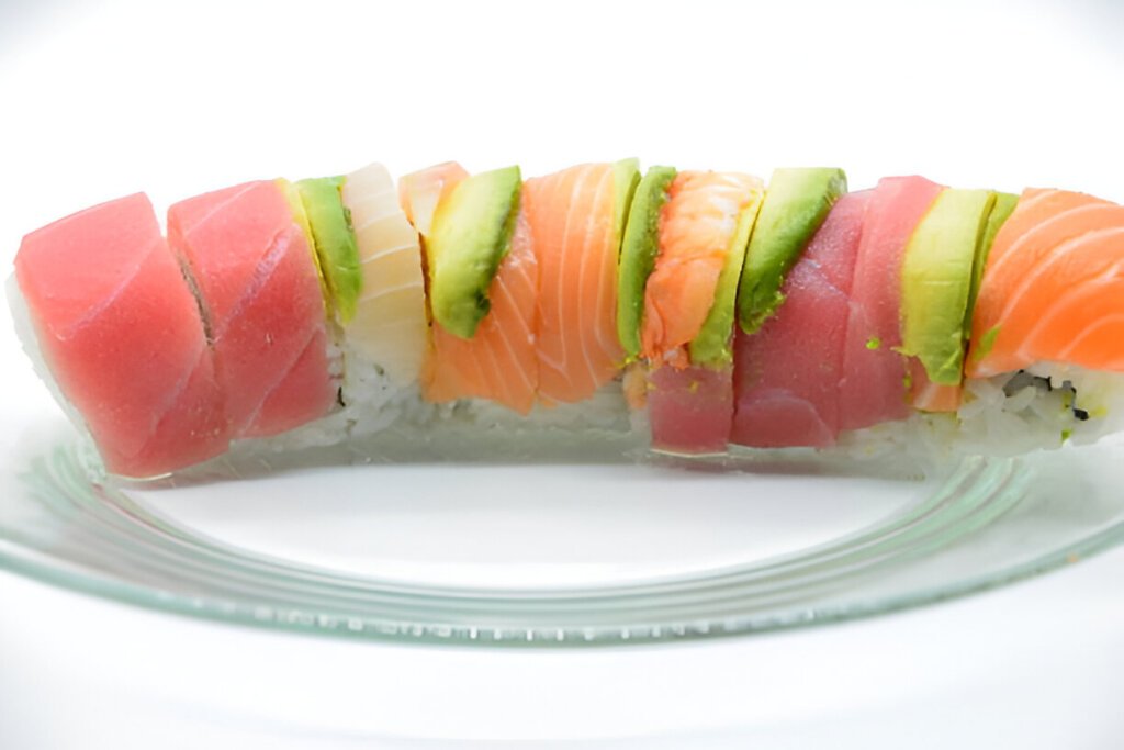 A beautifully arranged plate of sushi, showcasing various types including salmon sashimi, a California roll, and smoked salmon. The dish is garnished artistically, emphasizing the fresh ingredients and culinary details. The setting appears to be indoors.